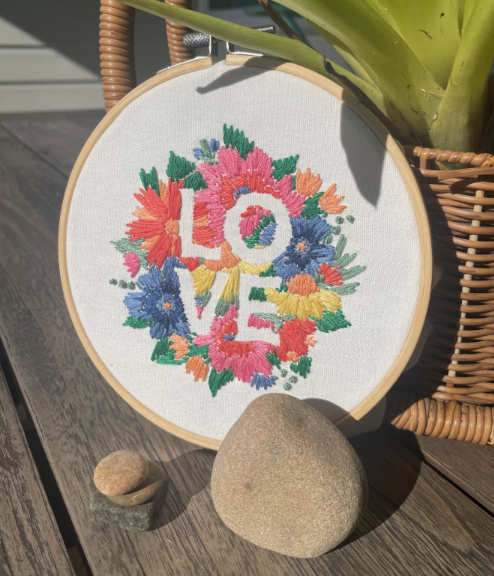  a long stitch sewing craft with the word LOVE on it and some rocks nearby