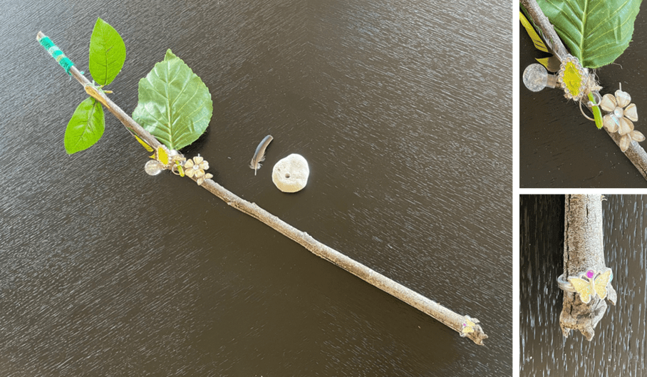 a picture of the wand with it's fake leaves, buttons and beads, laid on a black table
