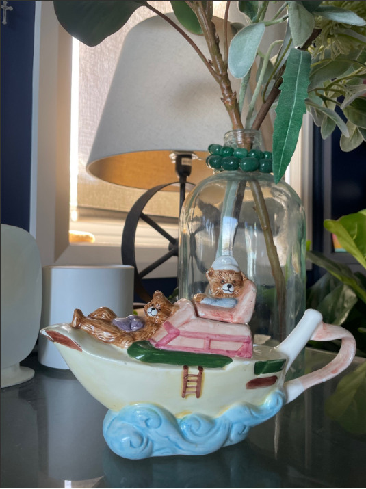 the picture shows an old porcelain gravy boat that is shaped like a boat - with two bears sailing on board